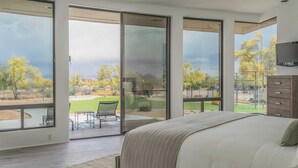 Ein Schlafzimmer mit einem großen Bett, einer Schiebetür zu einer Terrasse und einem an der Wand montierten Fernseher.