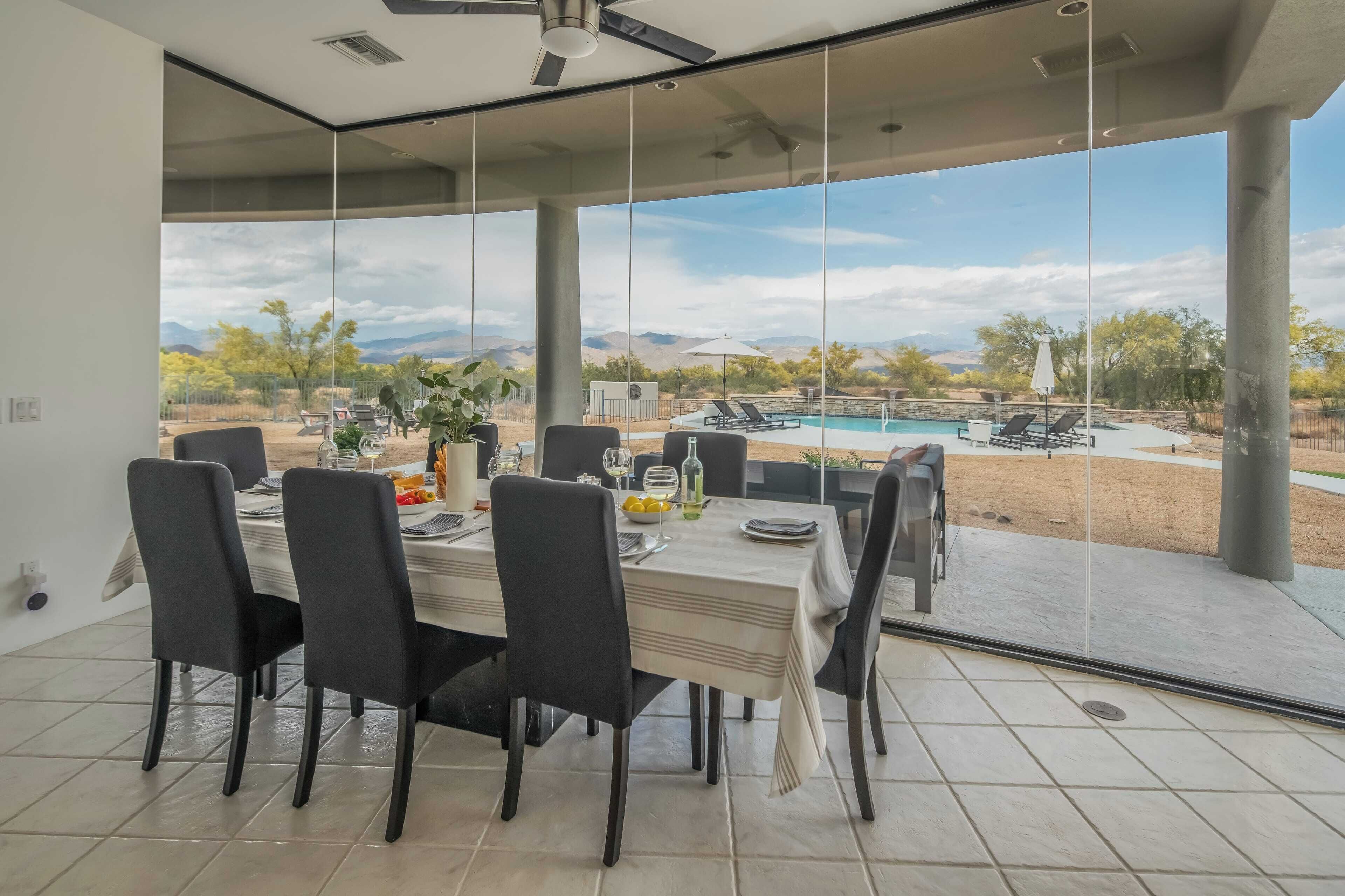 A dining area with a view of a swimming pool and mountains.