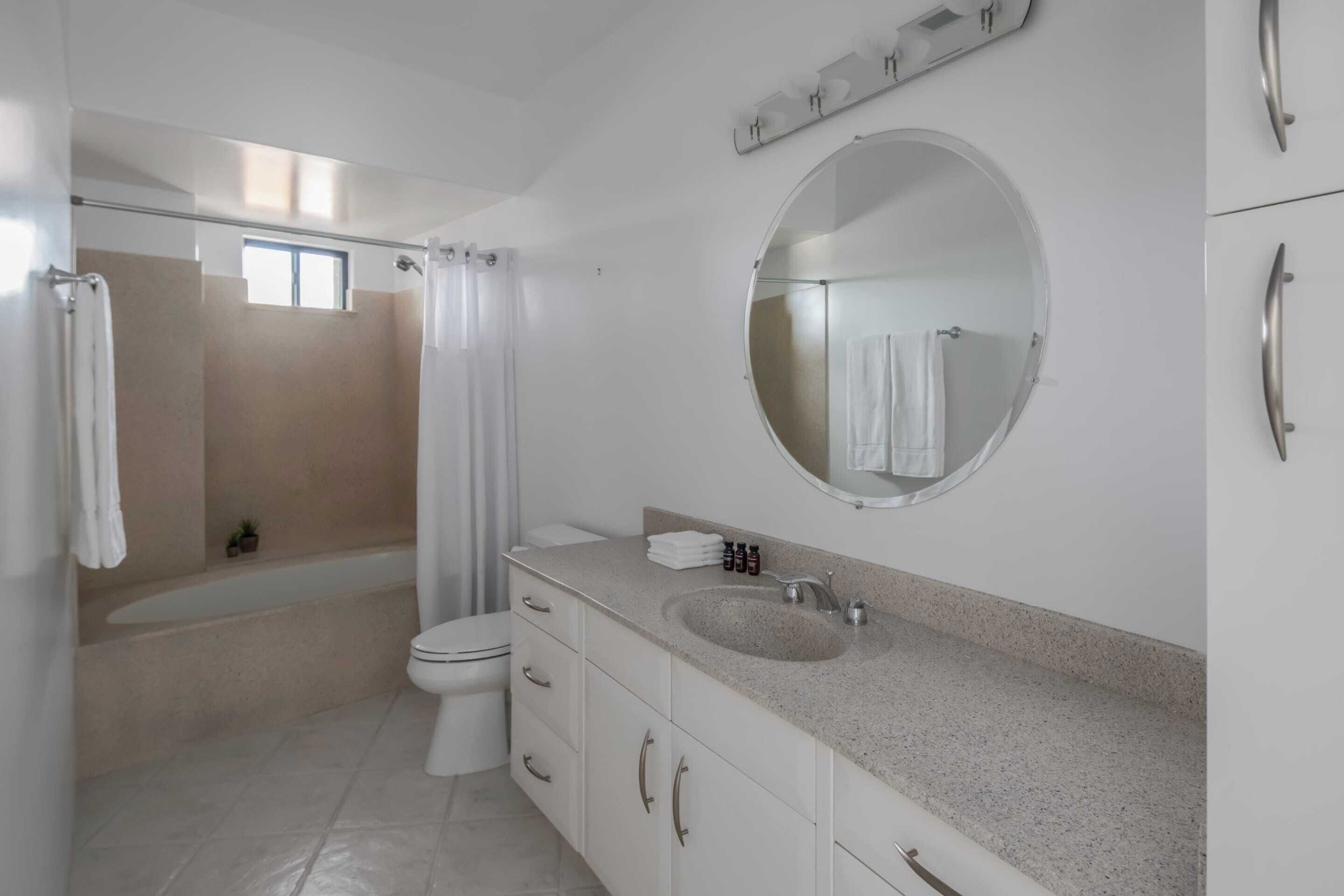 A modern bathroom with a bathtub, toilet, and a large mirror.