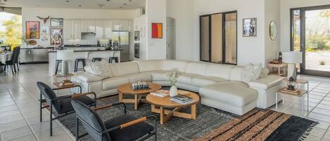 A modern living room with a sectional sofa, a coffee table, and a dining area with chairs.