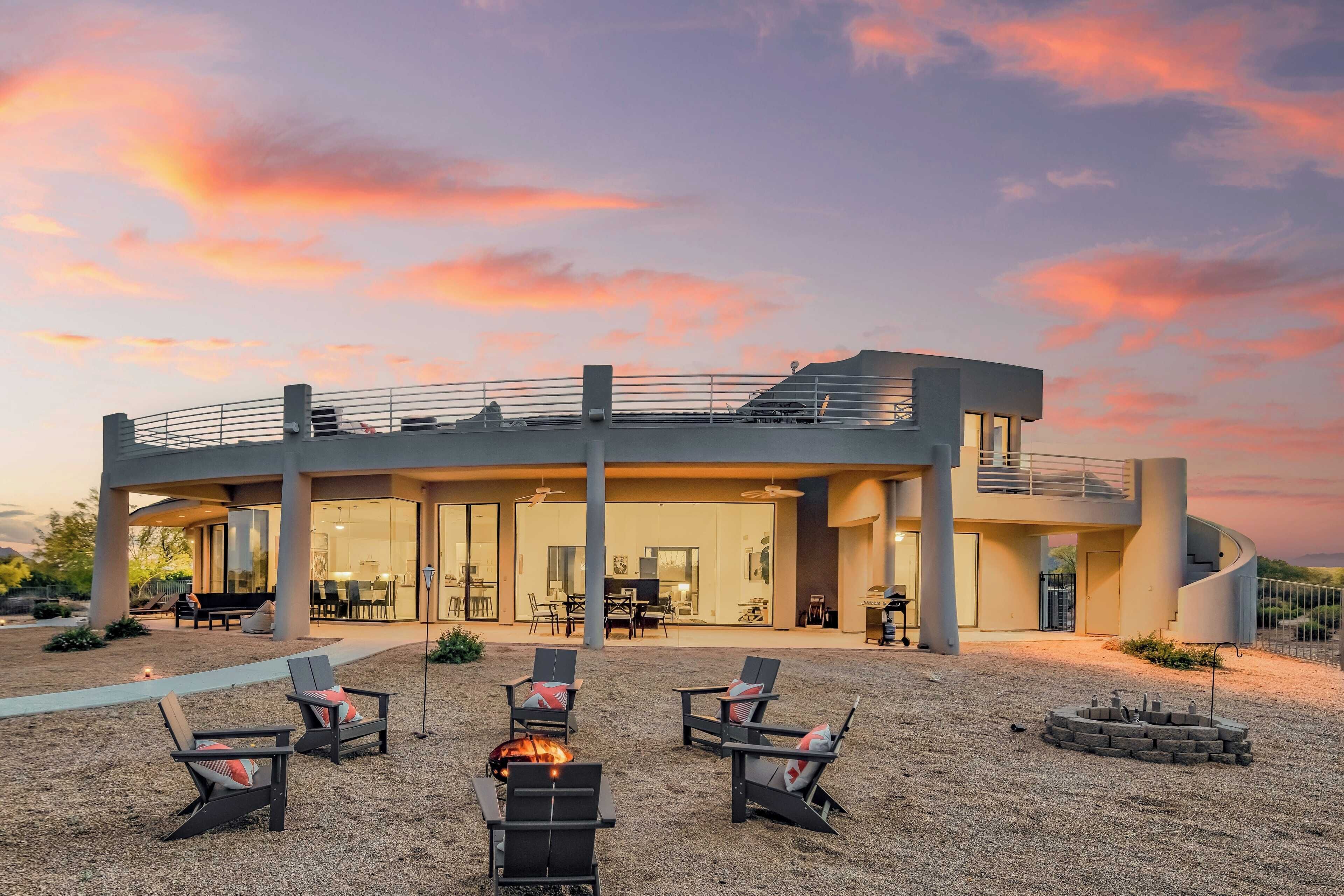 Ein modernes Haus mit geräumiger Terrasse, Sitzgelegenheiten im Freien und einer Feuerstelle.
