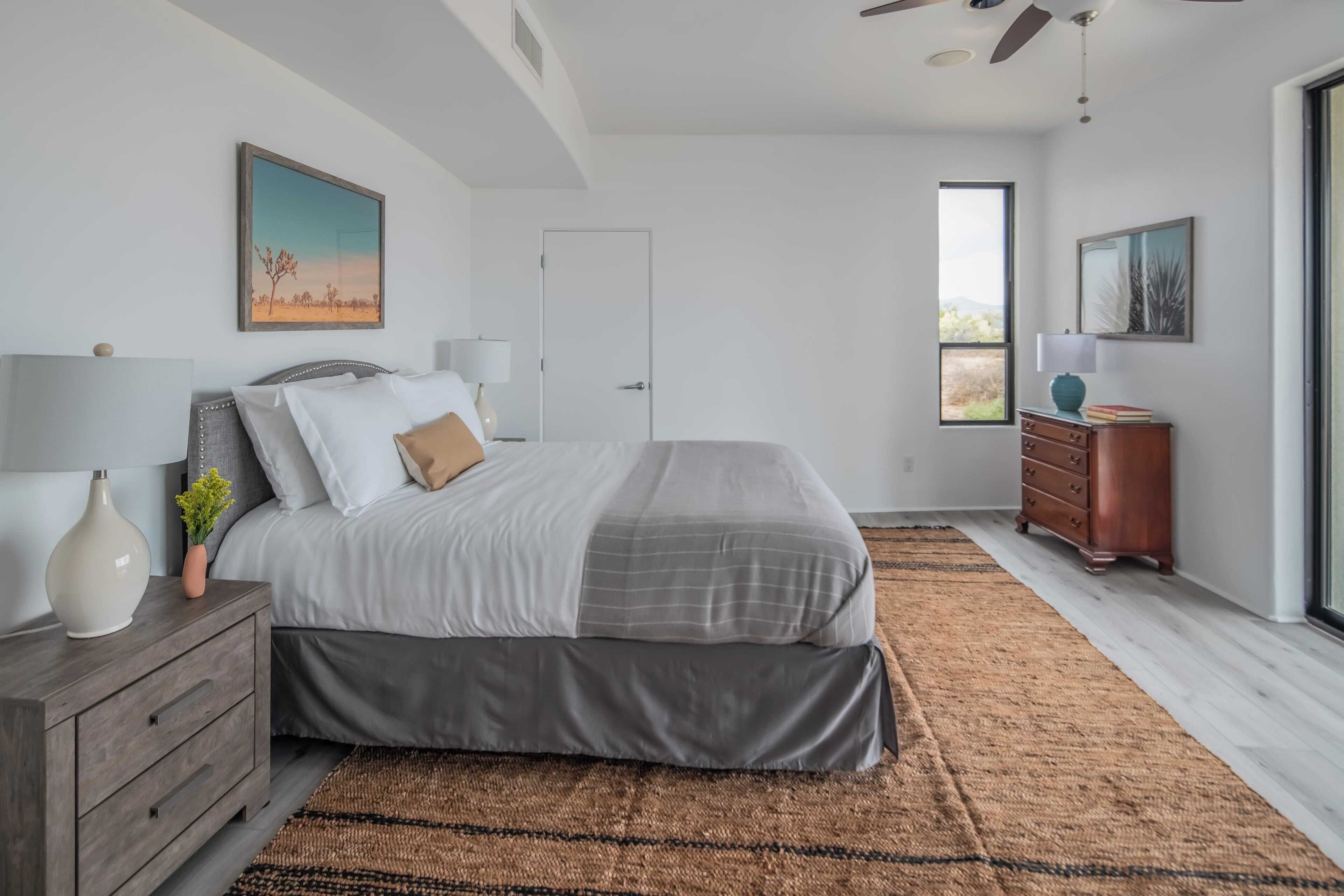 A bedroom with a bed, nightstands, a dresser, and a window.