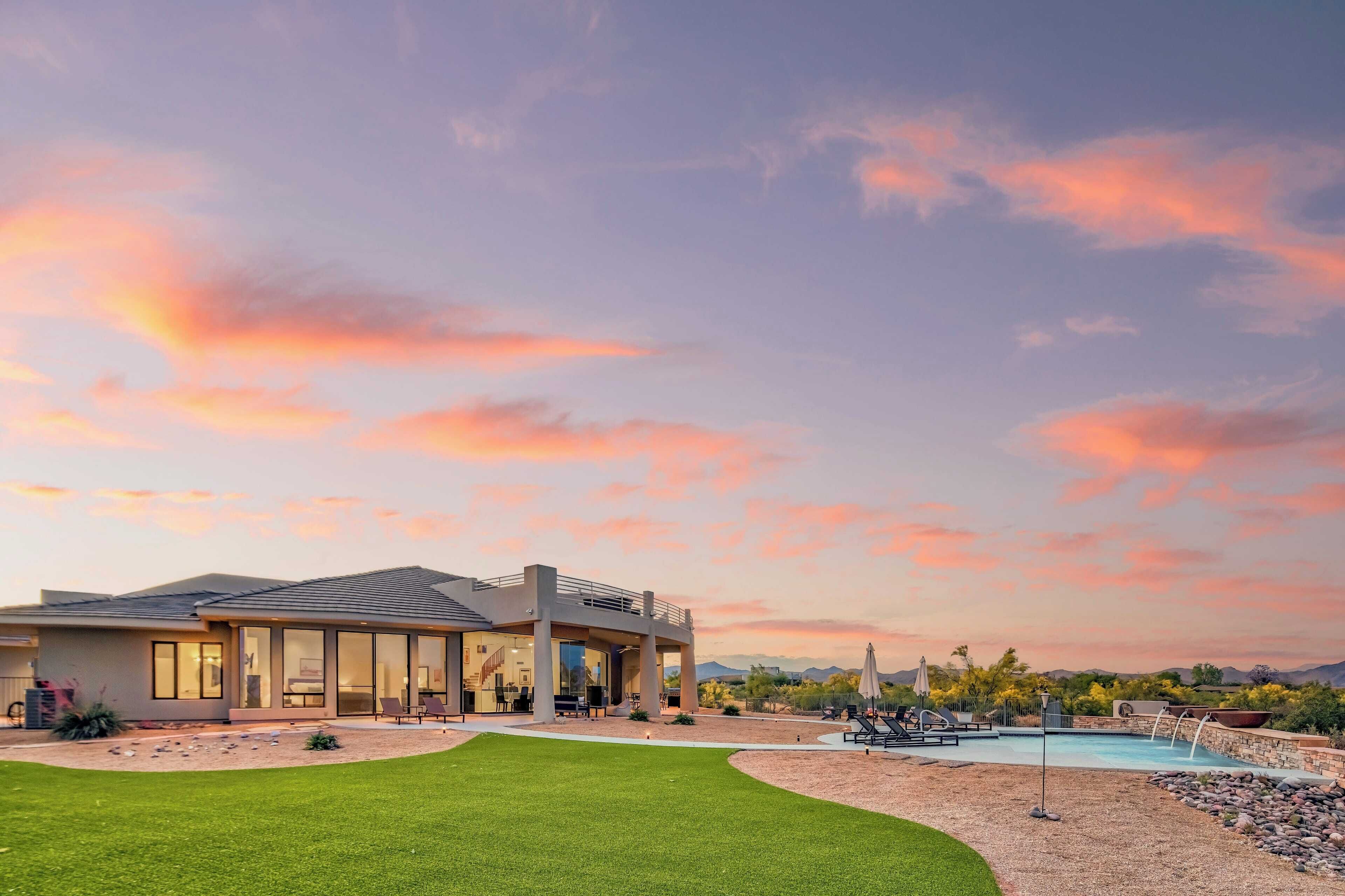 A modern house with a swimming pool, a covered patio, and a well-maintained lawn.