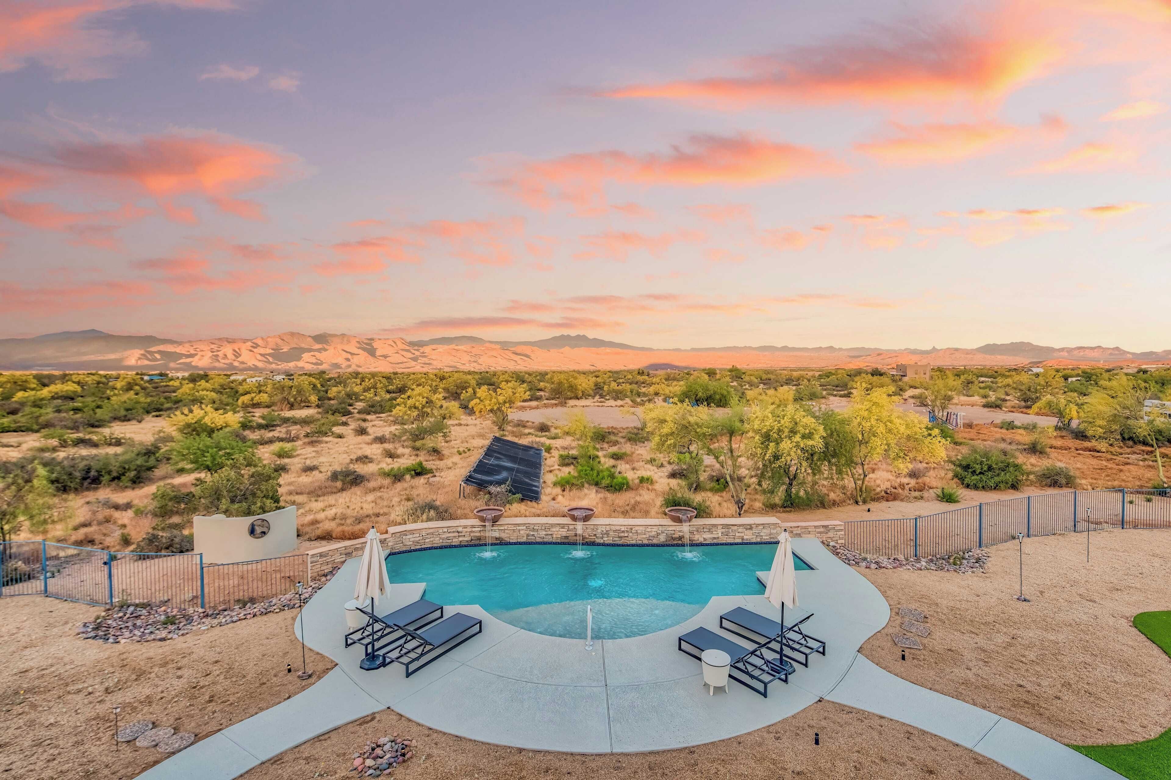A swimming pool with lounge chairs and a view of a desert landscape.