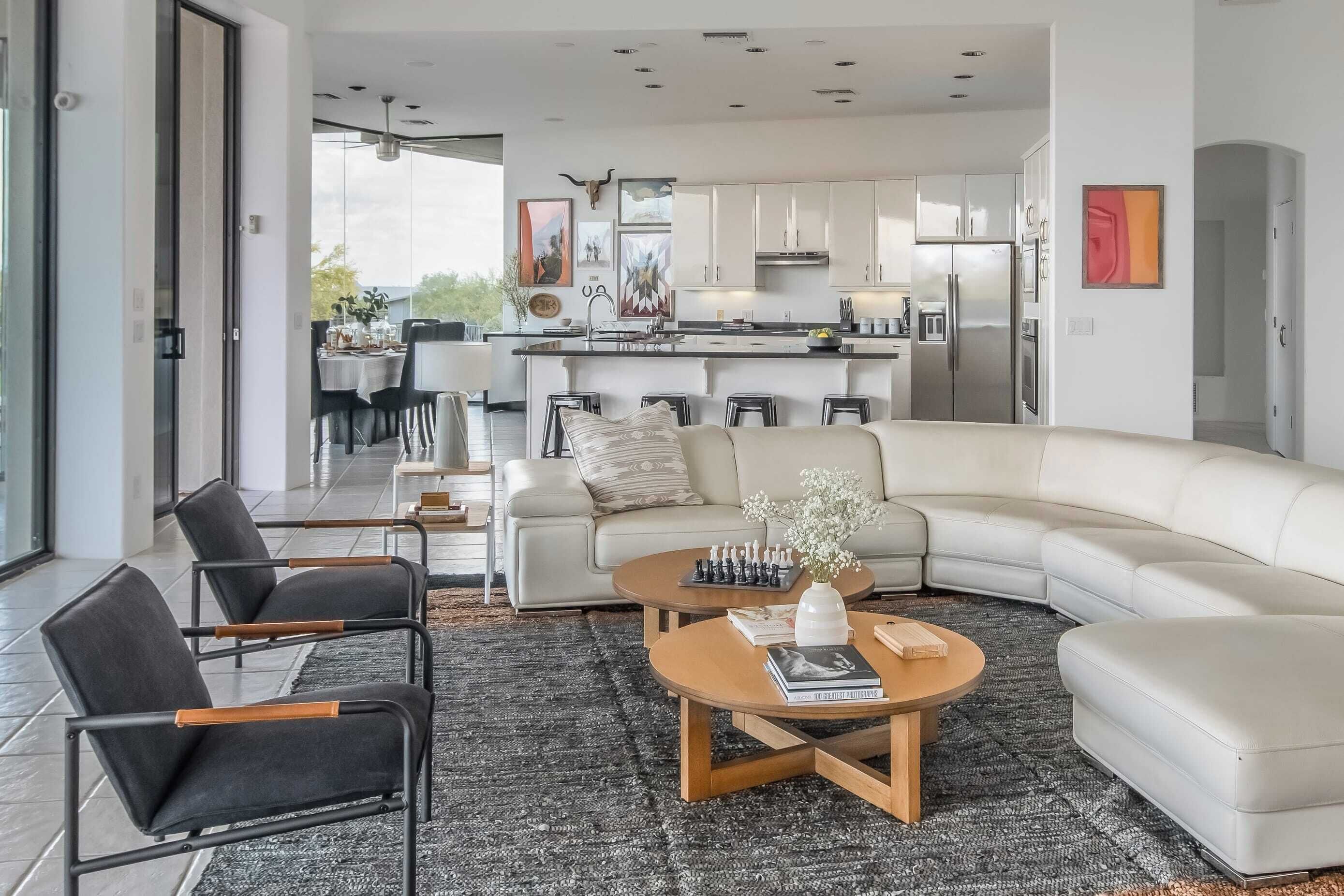 A modern living room with a sectional sofa, a coffee table, and a dining area with a kitchen in the background.
