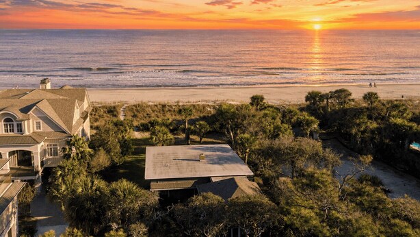 A coastal property with a large house, a flat-roofed structure, and a beach view. - Sandpiper by Avantstay Gorgeous Beachside Home w/ Spacious Yard & Chic Design (Hilton Head Island)