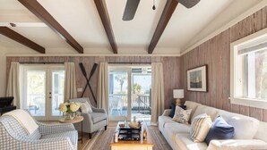 A living room with a wooden ceiling, a sofa, a chair, a coffee table, and a view of the outdoors. - Sandpiper by Avantstay Gorgeous Beachside Home w/ Spacious Yard & Chic Design (Hilton Head Island)