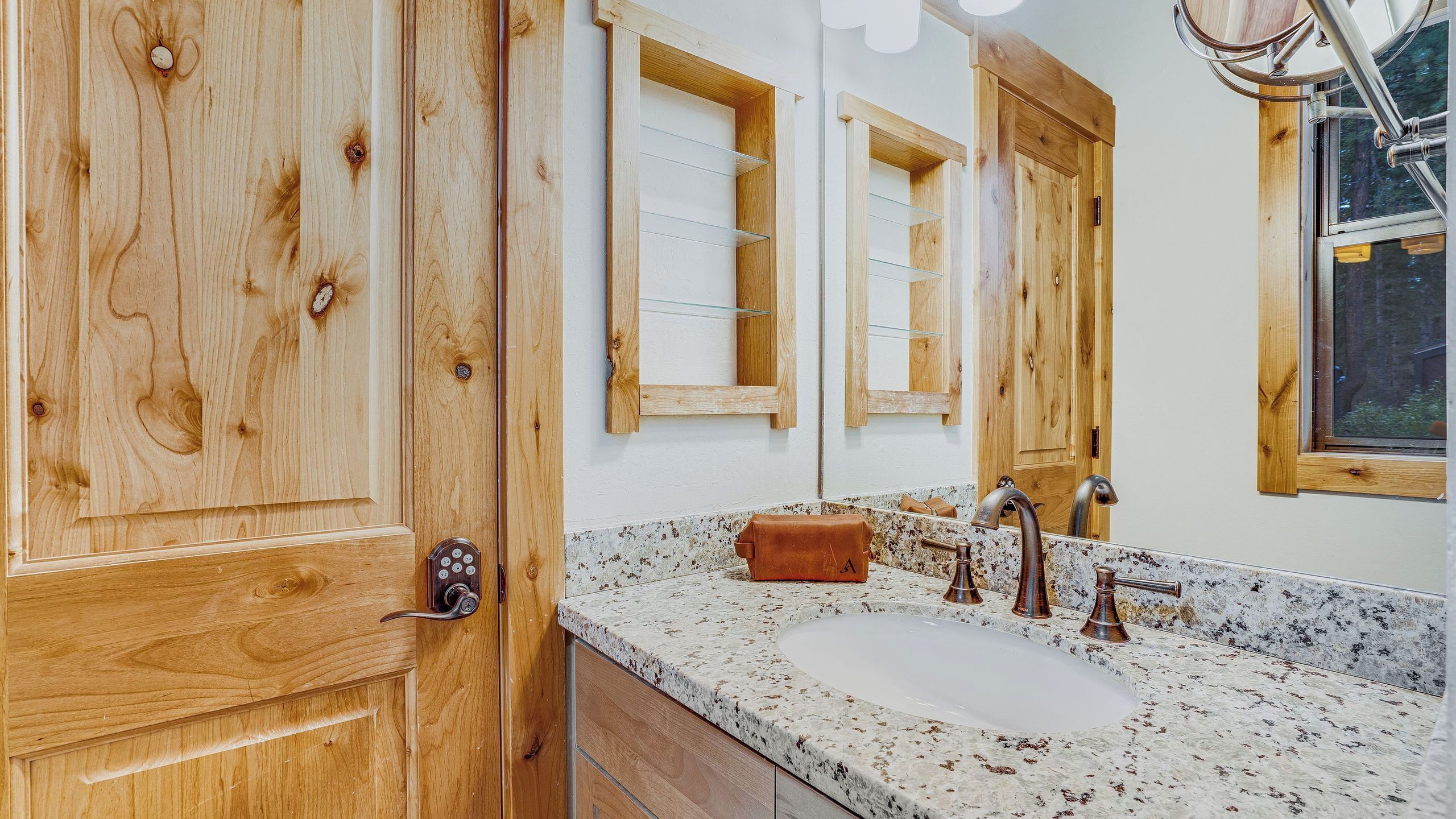 A bathroom with wooden cabinetry, a granite countertop, a sink, and a mirror.