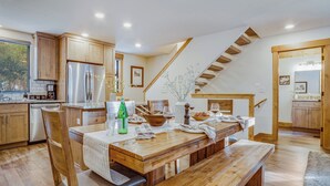 A kitchen with wooden cabinets, stainless steel appliances, and a dining area with a wooden table and bench. - Arroyo by Avantstay Peaceful Mountain Townhouse w/ Large Private Balcony (Truckee)