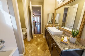 Une salle de bain moderne avec un grand miroir, un lavabo et une baignoire.