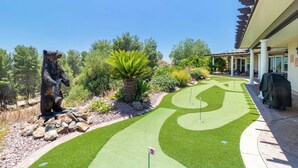 Un campo de golf con una estatua de oso, un césped bien cuidado y un edificio con un porche cubierto.