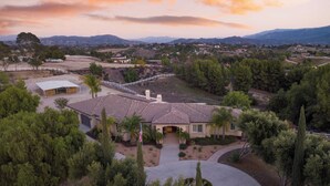 Propiedad residencial con una casa grande, un patio cubierto y un área vallada para montar a caballo.