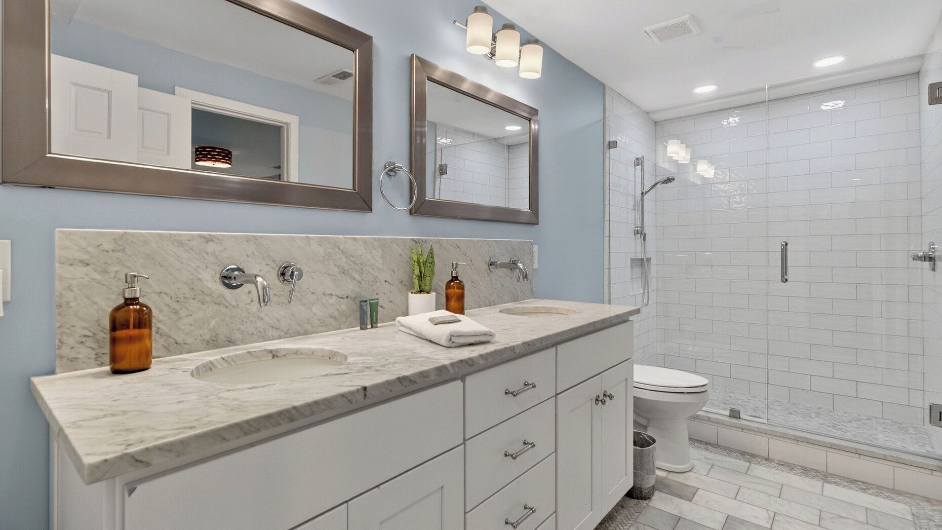 A bathroom with two sinks, a toilet, a shower, and a large mirror.