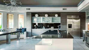 A modern kitchen with a central island, stainless steel appliances, and a seating area with a sofa and coffee table. - Preston by Avantstay 6BR Desert Oasis w/ Basketball Court, Pool & Hot Tub (Scottsdale)