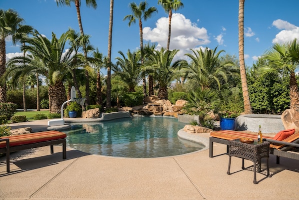 A pool area with lounge chairs and a small waterfall feature.