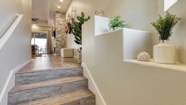 A staircase with wooden steps leading to a living area with a stone wall, a sofa, and a hanging guitar. - Eucalyptus by Avantstay Stunning Scottsdale Home w/ Communal Pool & Hot Tub (Scottsdale)
