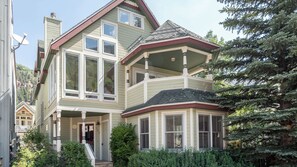 A multi-story house with a prominent bay window, a front porch, and a chimney.