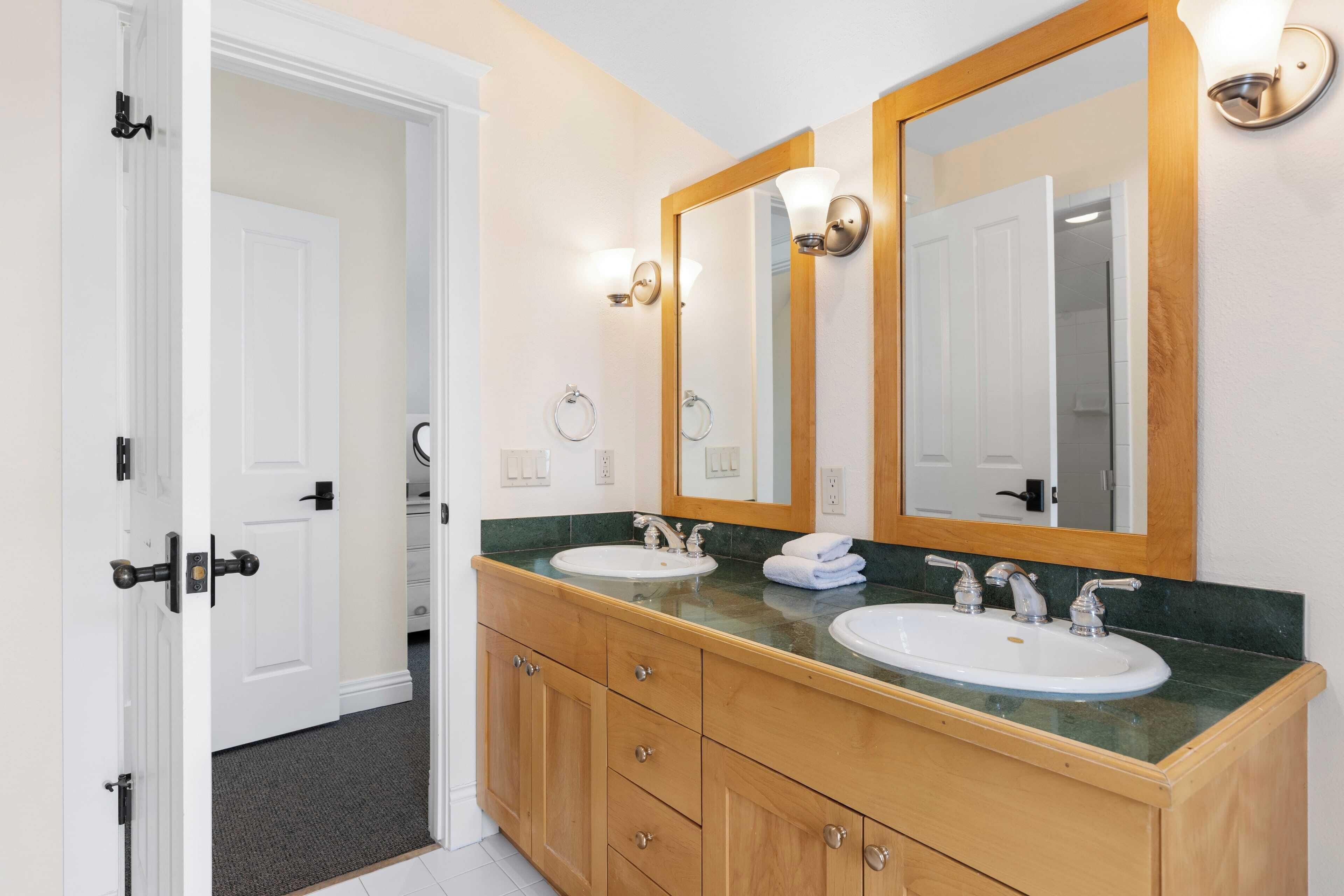 A bathroom with two sinks, wooden cabinets, and a large mirror.
