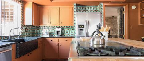 A kitchen with wooden cabinets, a stainless steel refrigerator, a gas stove, and a patterned backsplash.