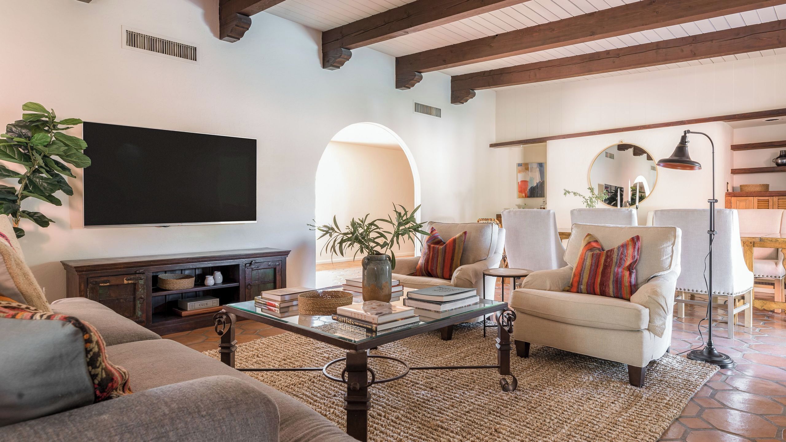 A living room with a television, sofa, armchair, coffee table, and a plant.