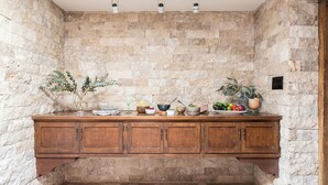 A stone wall with a wooden cabinet and various food items on top.