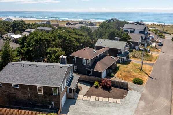 A residential area with houses, a driveway, and a beach in the background.