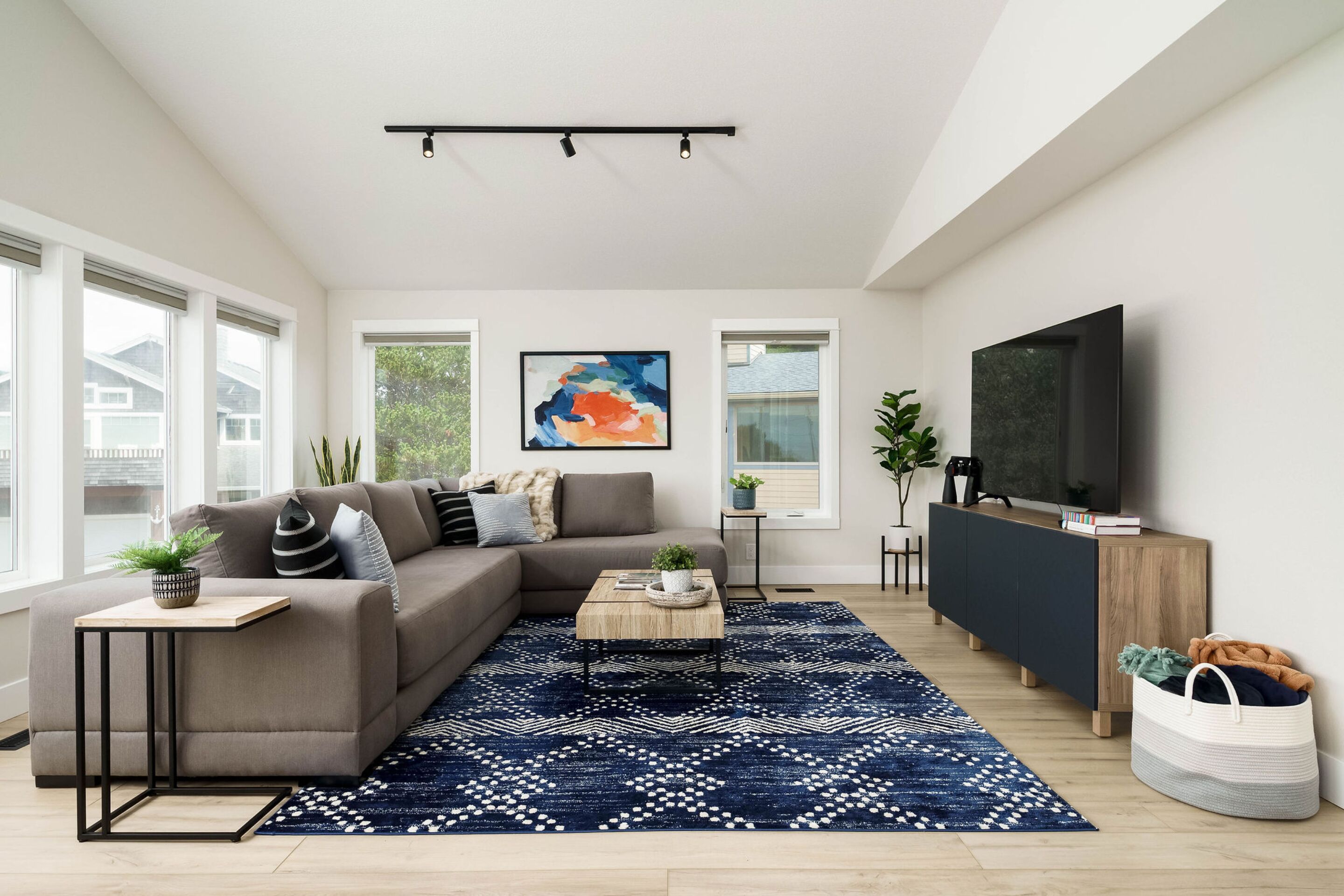 A modern living room with a sectional sofa, a coffee table, a TV, and a patterned rug.