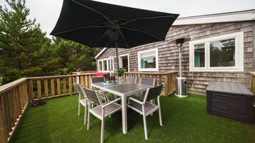 A deck with a table and chairs, a trash can, and a shed.