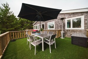A deck with a table and chairs, a trash can, and a shed.