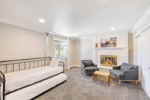 Relax in this serene bedroom with a comfortable sofa, neatly made bed, and cozy fireplace.
