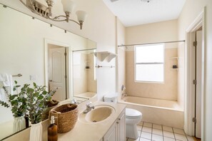 A bathroom with a large mirror, a sink, a toilet, and a bathtub.