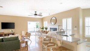 Una cocina moderna con una isla grande, taburetes blancos tipo barra y un comedor con mesa y sillas.