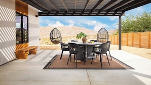 An outdoor patio with a round table, black chairs, and a potted plant. - Chicory by Avantstay Modern Desert Retreat w/ Hot Tub (Joshua Tree)