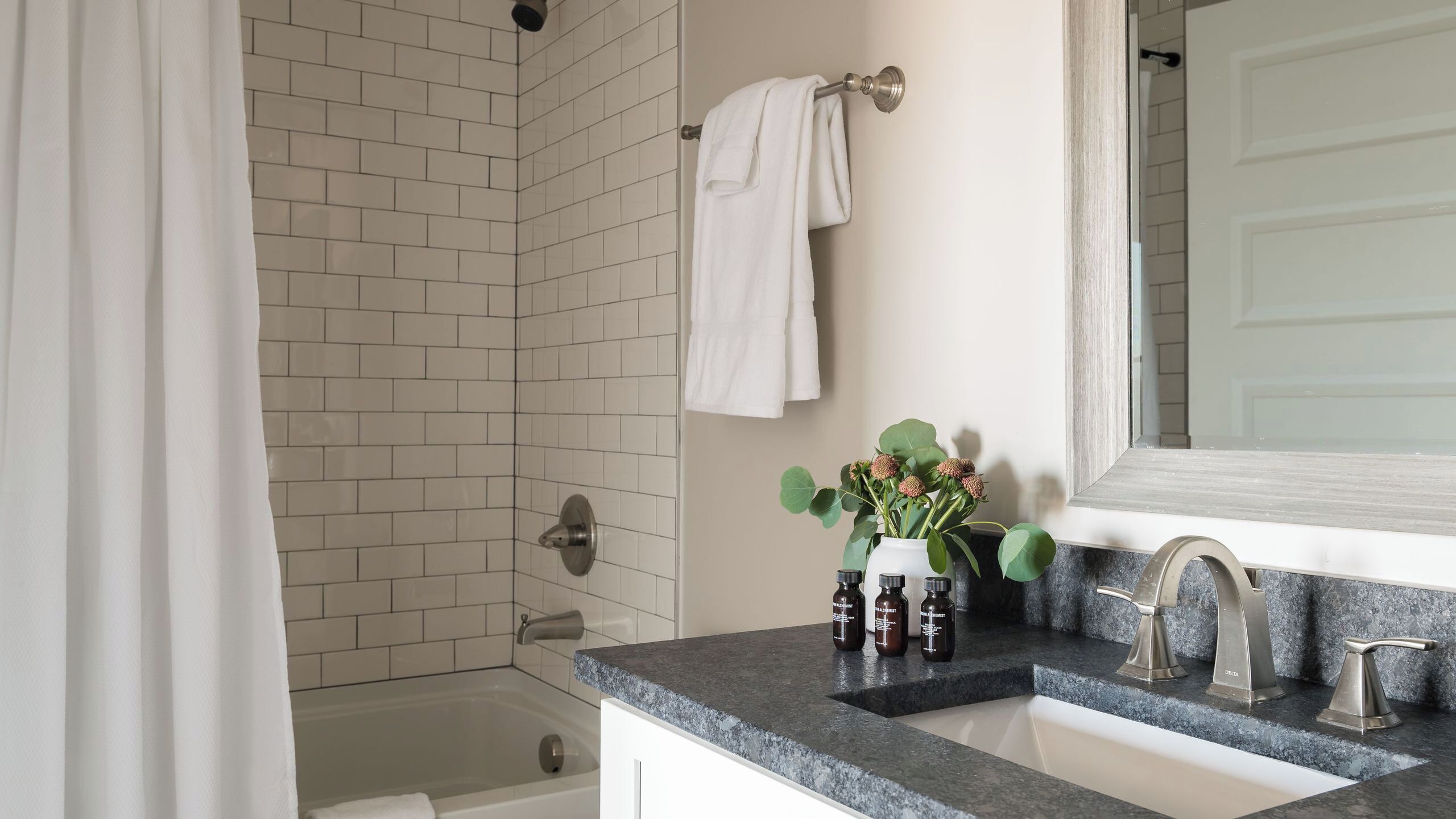 Un bagno moderno con vasca, lavandino con piano in marmo e zona doccia.