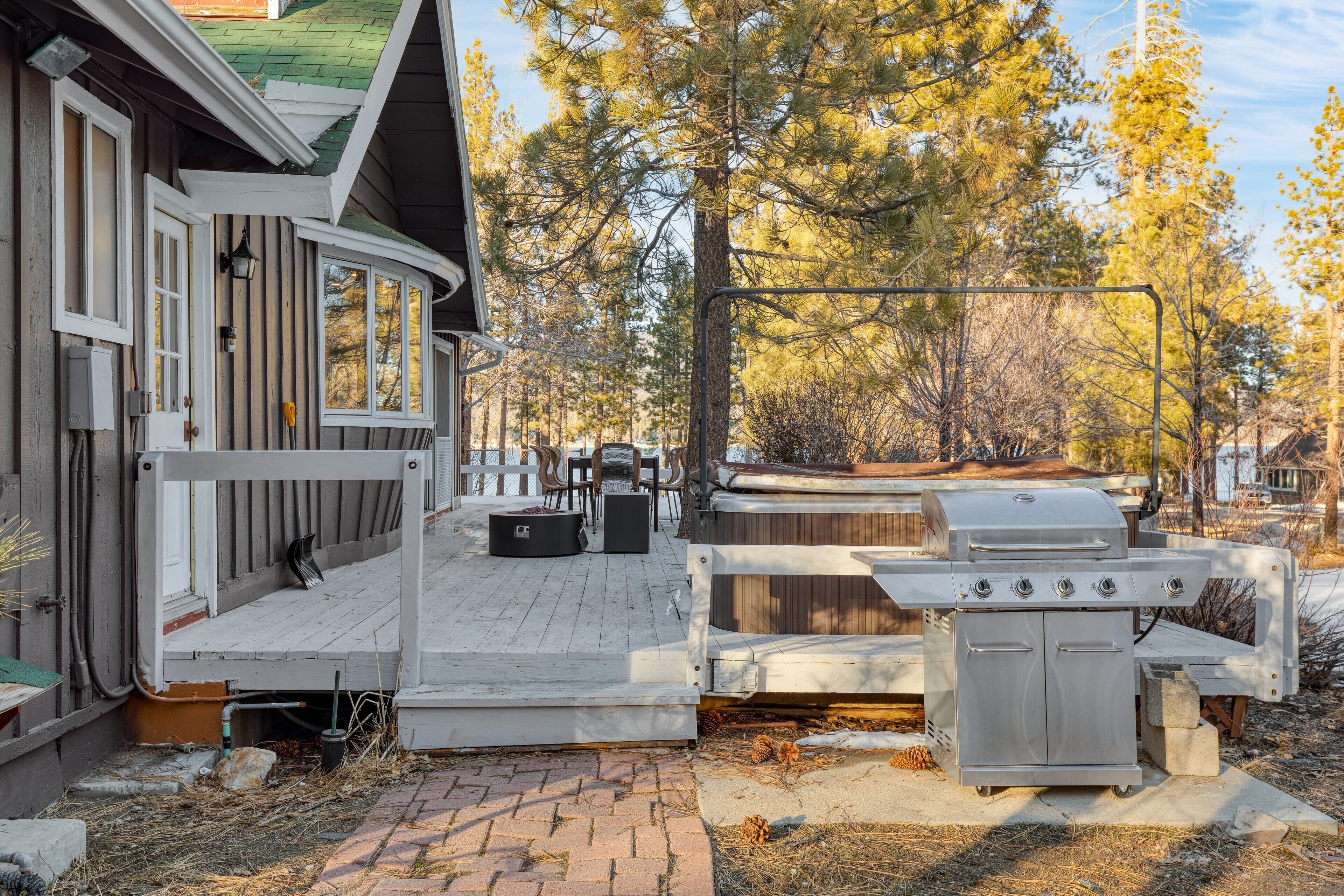 A wooden deck with outdoor furniture, a grill, and a covered seating area.