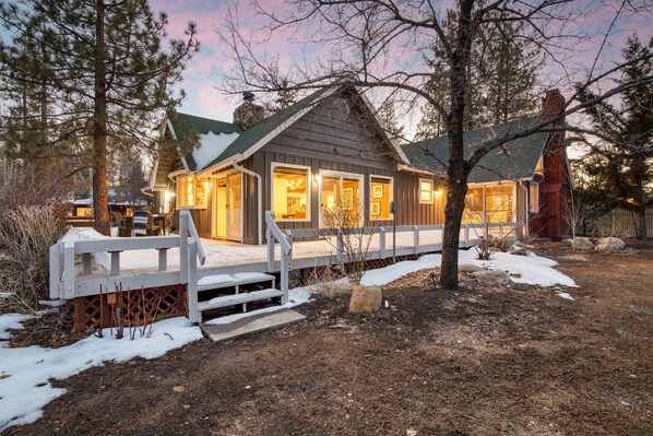 Enjoy the serene outdoors from the covered deck or cozy porch of this cabin-style home, surrounded by mature trees and a natural landscape.