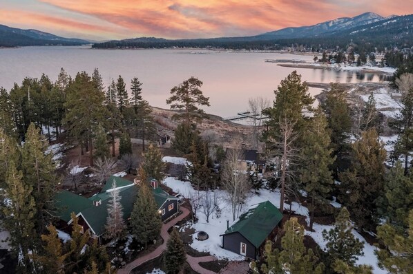 A residential area with houses surrounded by snow-covered trees and a lake.