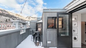 A modern building with a balcony, outdoor seating, and framed pictures on the wall. - New San Juan 303 by Avantstay Modern Penthouse w/ Deck Overlooking Main Street (Telluride)