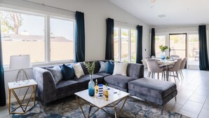 Ein modernes Wohnzimmer mit einer Eckcouch, einem Couchtisch und einem Essbereich mit Tisch und Stühlen.