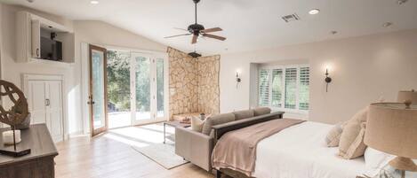Un dormitorio con cama, ventilador de techo, sofá, escritorio y ventana con persianas.