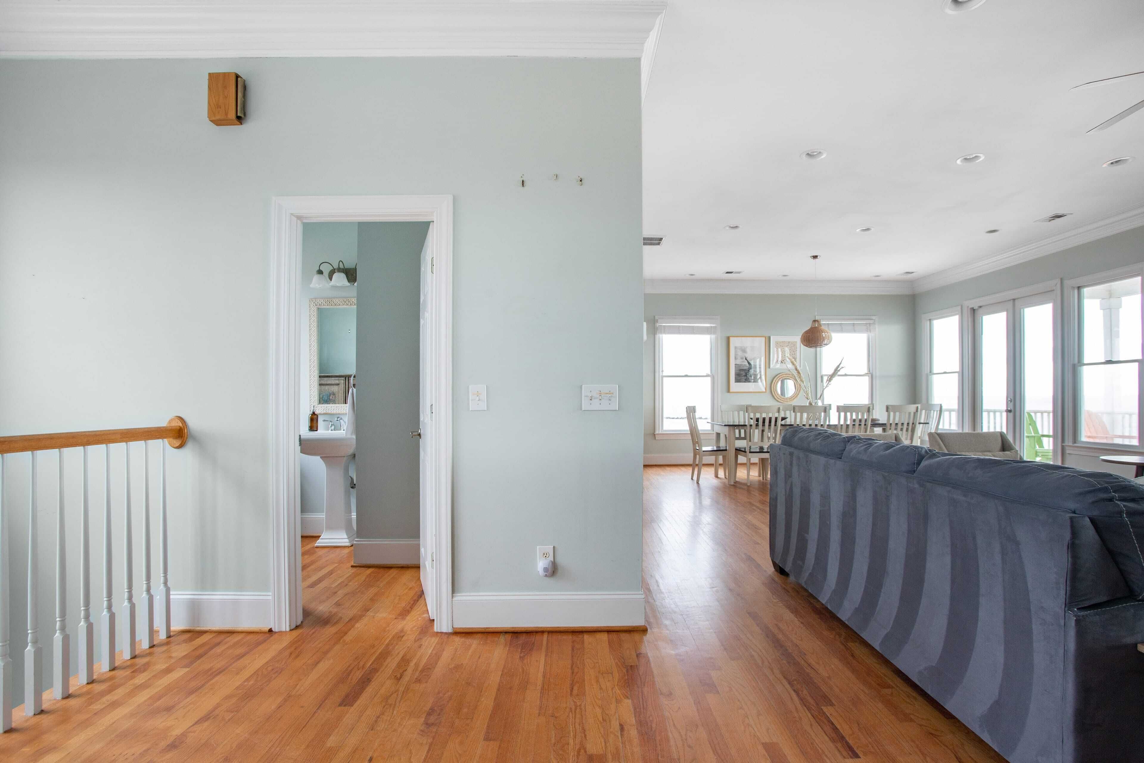 Un soggiorno spazioso con parquet, un ampio divano modulare grigio e un'area pranzo con tavolo e sedie.