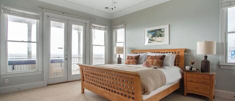 A bedroom with a wooden bed, two bedside tables, a ceiling fan, and large windows.
