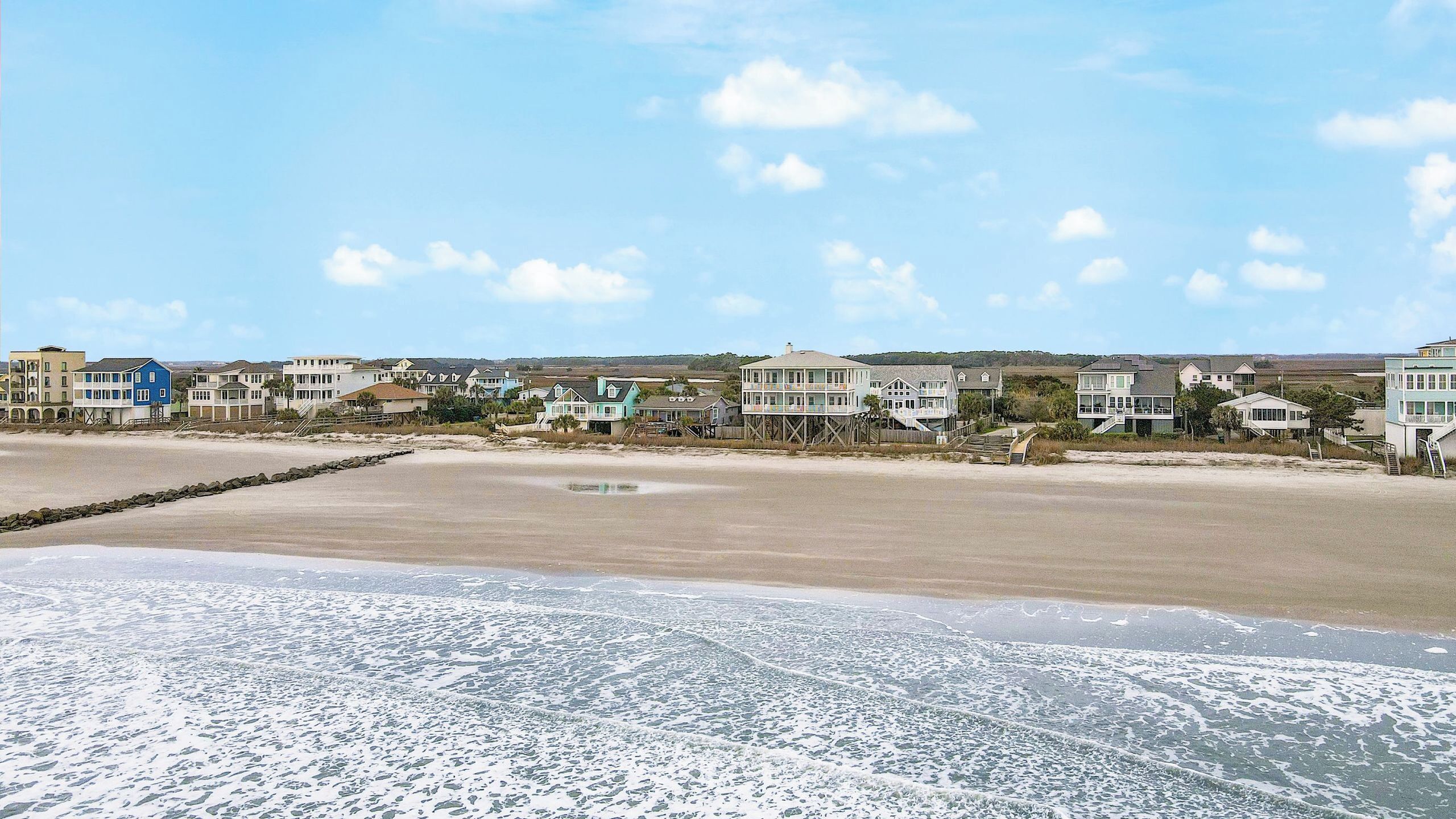 En ejendom ved stranden med flere huse, en sandstrand og havudsigt.