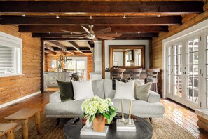 A log cabin interior with a sofa, coffee table, and a ceiling fan. - Chateau Syrah by Avantstay Picturesque Estate w/ Pool, Hot Tub, Table Tennis & Pool Table New Pickleball Court + Basketball Hoop (Temecula)