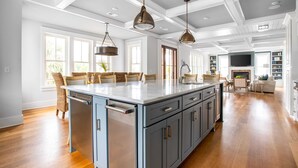 A spacious kitchen with a large island, wooden flooring, and pendant lighting. - 1blck to Beach, Pool, Outdoor Kitchen, Game Room Pelican by Avantstay (Isle of Palms)