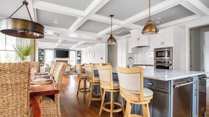 A modern kitchen with white cabinetry, stainless steel appliances, and a central island. - 1blck to Beach, Pool, Outdoor Kitchen, Game Room Pelican by Avantstay (Isle of Palms)