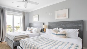 A hotel room with two beds, a ceiling fan, a window with curtains, and a framed picture on the wall. - 1blck to Beach, Pool, Outdoor Kitchen, Game Room Pelican by Avantstay (Isle of Palms)