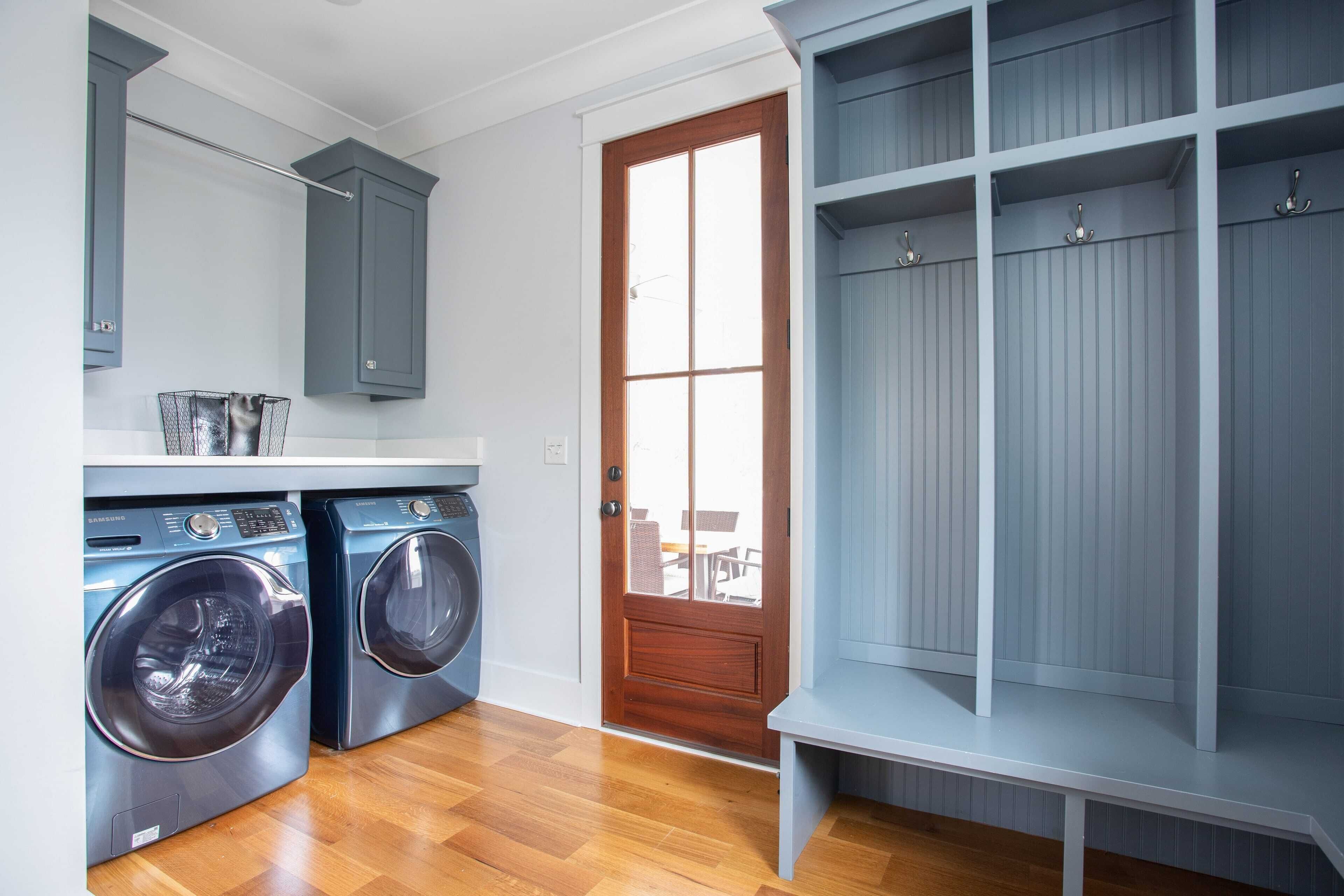 A laundry room with two front-loading washing machines, a wooden door, and a built-in shelving unit.