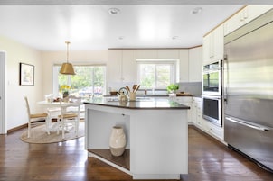 Una cocina moderna con armarios blancos, un refrigerador de acero inoxidable y una isla central.