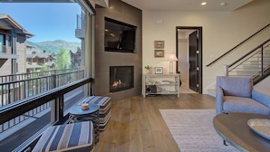 A modern living room with a fireplace, a balcony with outdoor seating, and a view of the mountains. - Juniper Landing 3 Bedroom by Avantstay Condo in Park City Mountain Resort w/ Pool, Hot Tub & Gym (Park City)